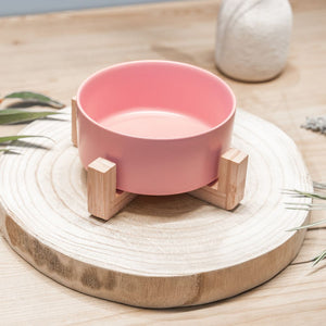 Petal pink ceramic pet bowl side view with eco-friendly bamboo stand on wooden board by Pet Store Collective. Dishwasher safe ceramic bowl, chip-resistant, and holds up to 850ml of pet food or water.