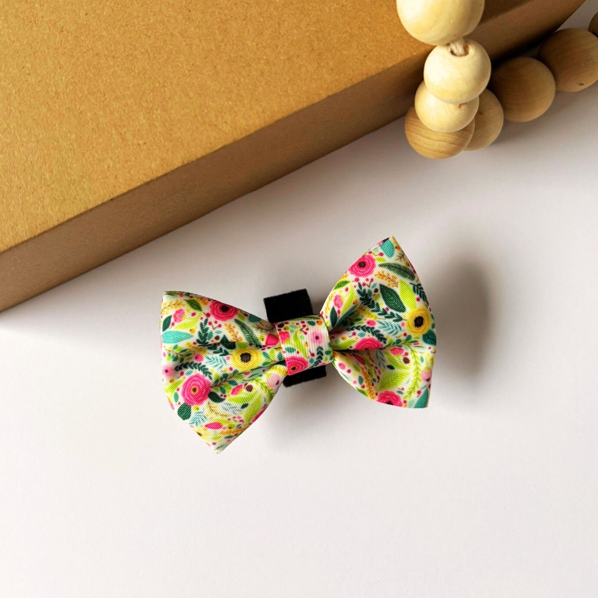 Top view of our small Bloom Floral Dog Bowtie in pink floral design with greenery accents. Lightweight, durable, and designed with an easy velcro attachment to suit both cats and dogs.