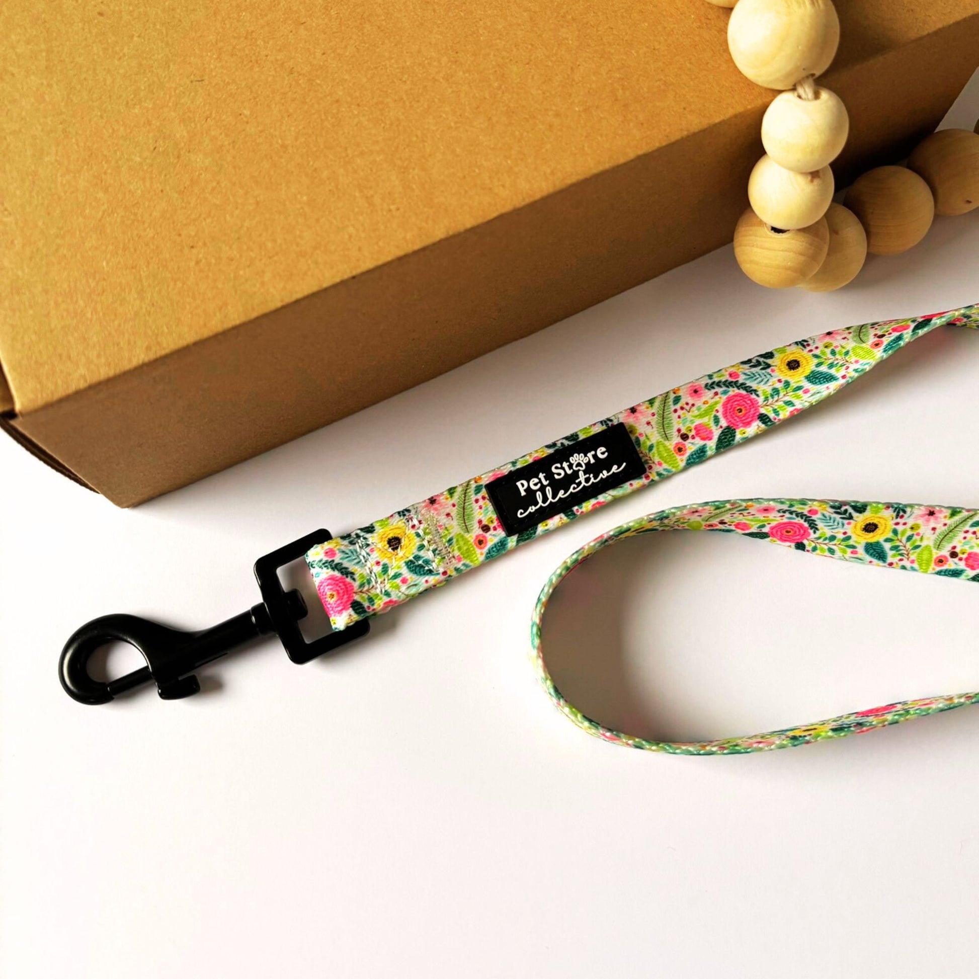 Top view of our Bloom Floral Dog Lead in pink roses and greenery print. Made from strong polyester webbing with inner padded neoprene handle for comfort. Featuring our sturdy metal swivel clip for tangle free walks. Available in Small (152cm x 1.5cm), Medium (152cm x 2cm), and Large (152cm x 2.5cm).
