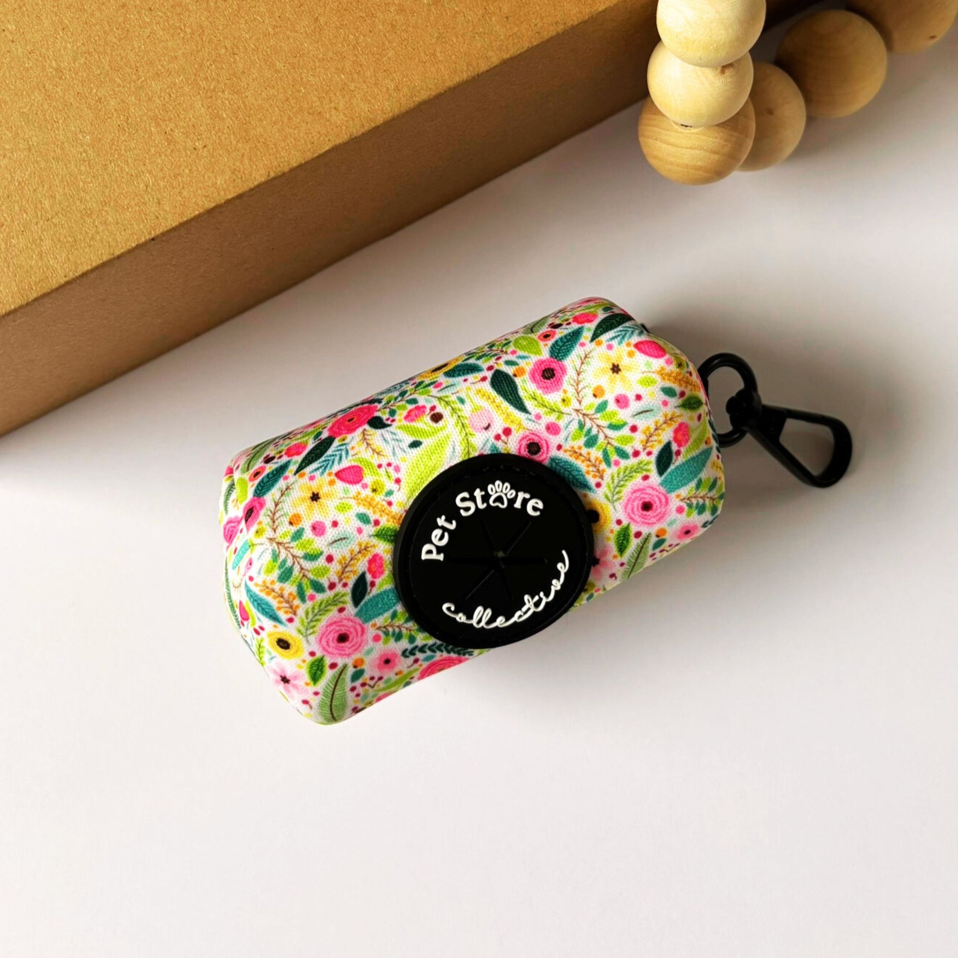 Angled view of our floral dog poop bag holder. Our Bloom collection print in pink flowers and green leaves, lightweight and durable neoprene with secure clip.
