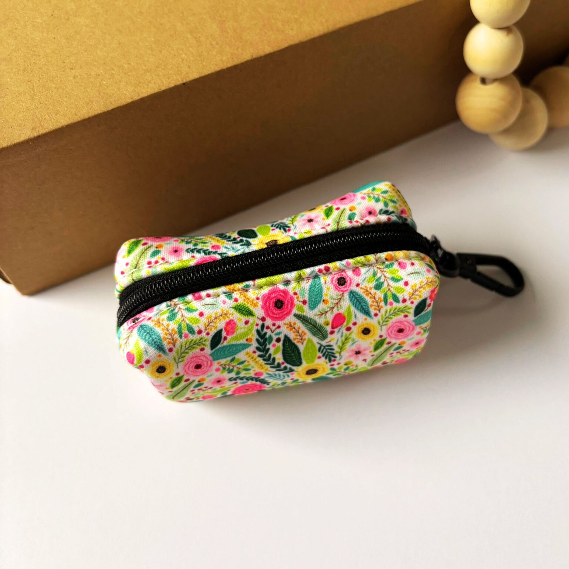 Back view of our Bloom Floral Dog Poop Bag Holder. Showcasing blooming pink roses and greenery on quick-dry neoprene. With a secure zipper closure and black metal clip for easy dog lead attachment.