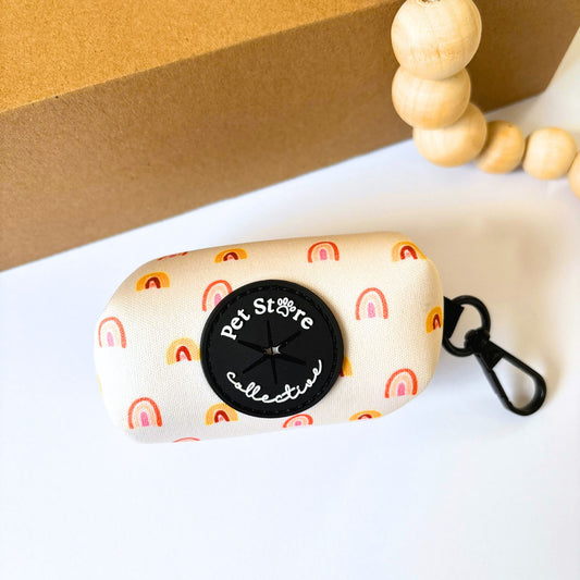 Our Boho Rainbow dog poop bag holder in soft yellow and golden rainbow print. Featuring our black rubber dispenser for quick waste bag access and durable metal clip for easy leash attachment.