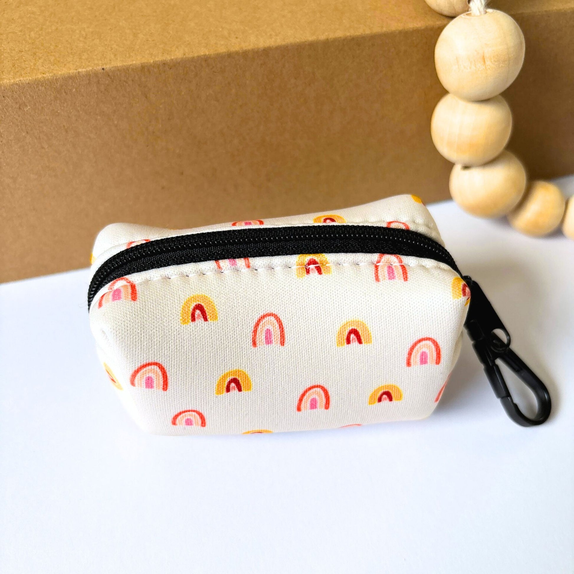 Our Boho Rainbow dog poop bag holder with zip closure, soft rainbow print in yellow and peach tones. Crafted from durable quick-dry neoprene with secure clip for daily walks.