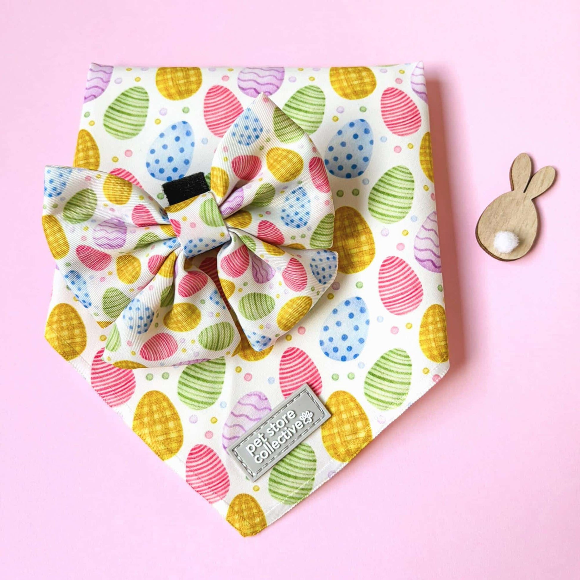 Easter dog bandana and bow tie set with colourful egg print styled on pink background with bunny prop. Fits dogs and cats with neck size up to 39cm, lightweight and comfortable pet accessory.