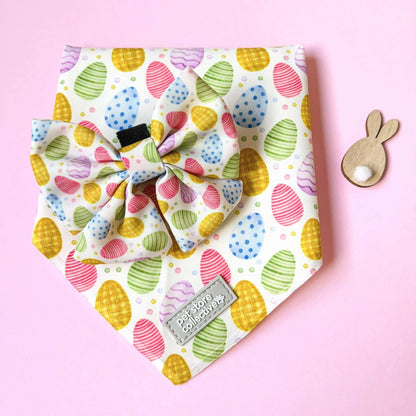 Easter dog bandana and bow tie set with colourful egg print styled on pink background with bunny prop. Fits dogs and cats with neck size up to 39cm, lightweight and comfortable pet accessory.