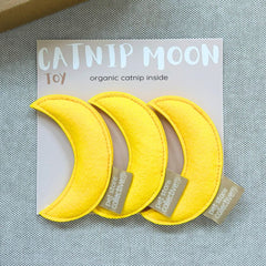Pet Store Collective handmade yellow moon catnip toys pack of three with organic catnip, displayed on grey linen with PSC gift box in the left top hand corner.