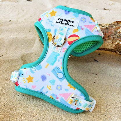 Close-up of our limited release Summer Bliss Adjustable Dog Harness resting on log with sand behind. Showcasing our stunning turquoise padded rim, beach-inspired print, and soft neoprene fabric. Designed in Australia by Pet Store Collective for cool, comfortable summer adventures.