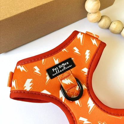 Close-up of our Thunderbolt Adjustable Dog Harness featuring a vibrant orange base with white thunderbolts and the sturdy front D-ring clip for secure training or daily adventures.