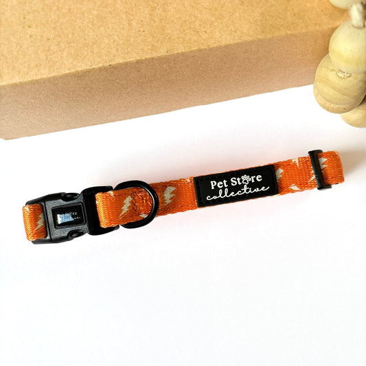 Front view of our Thunderbolt Dog Collar in bright orange with bold white thunderbolt design. Pet Store Collective logo, quick-dry neoprene padding and 4-point locking buckle for dogs.