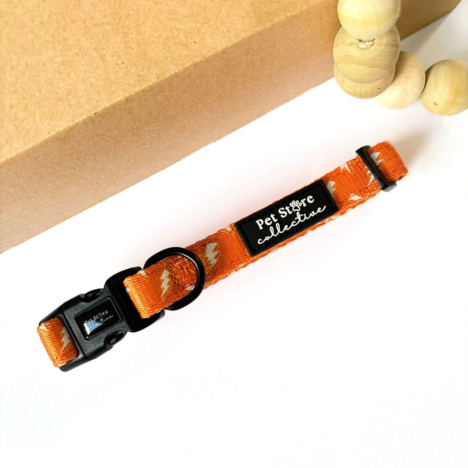 Angled shot of our Thunderbolt Dog Collar in vibrant orange with white thunderbolt design. Featuring a secure buckle, D-ring for lead attachment, and adjustable fit for small to large dogs.