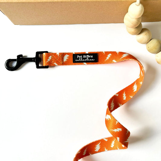 Our Thunderbolt Dog Lead in vibrant orange with white thunderbolt print. Featuring polyester wedding leash with neoprene-lined handle, durable dog accessory designed in Australia by Pet Store Collective.