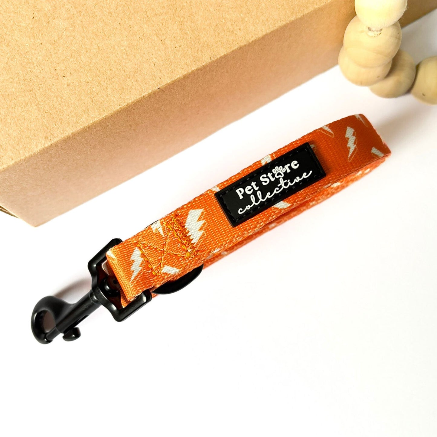 Close-up of our Thunderbolt Dog Lead clasp and Pet Store Collective logo. Showcasing bold orange with white thunderbolt design, lightweight yet sturdy dog walking lead for daily use.