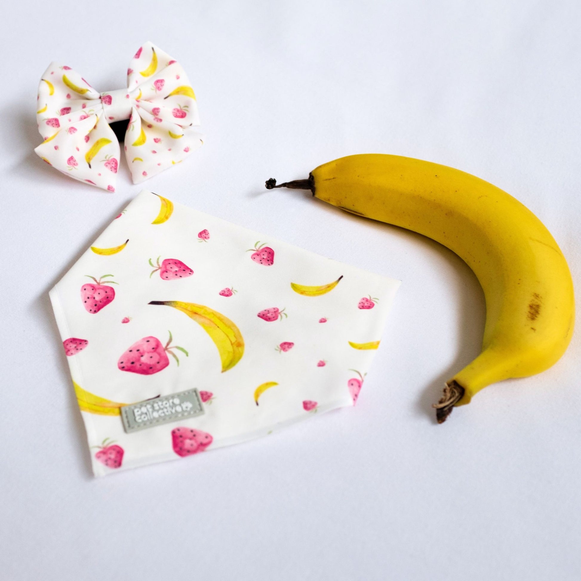 Our Tropical Dog Bandana and Matching Sailor Bowtie set in exclusive strawberry and banana print, perfect for stylish pets, photographed on a white background.